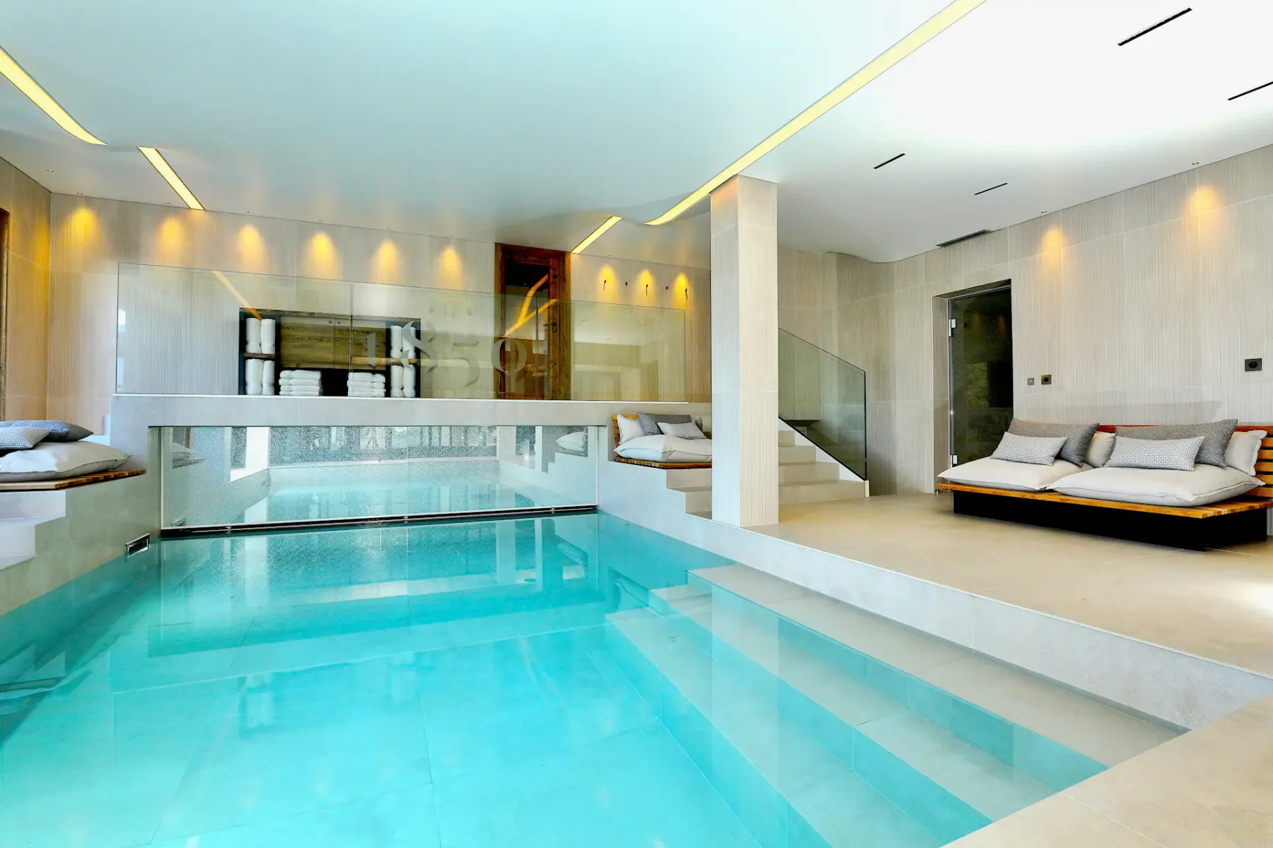 Piscina interior con agua azul clara y asientos integrados a los lados.