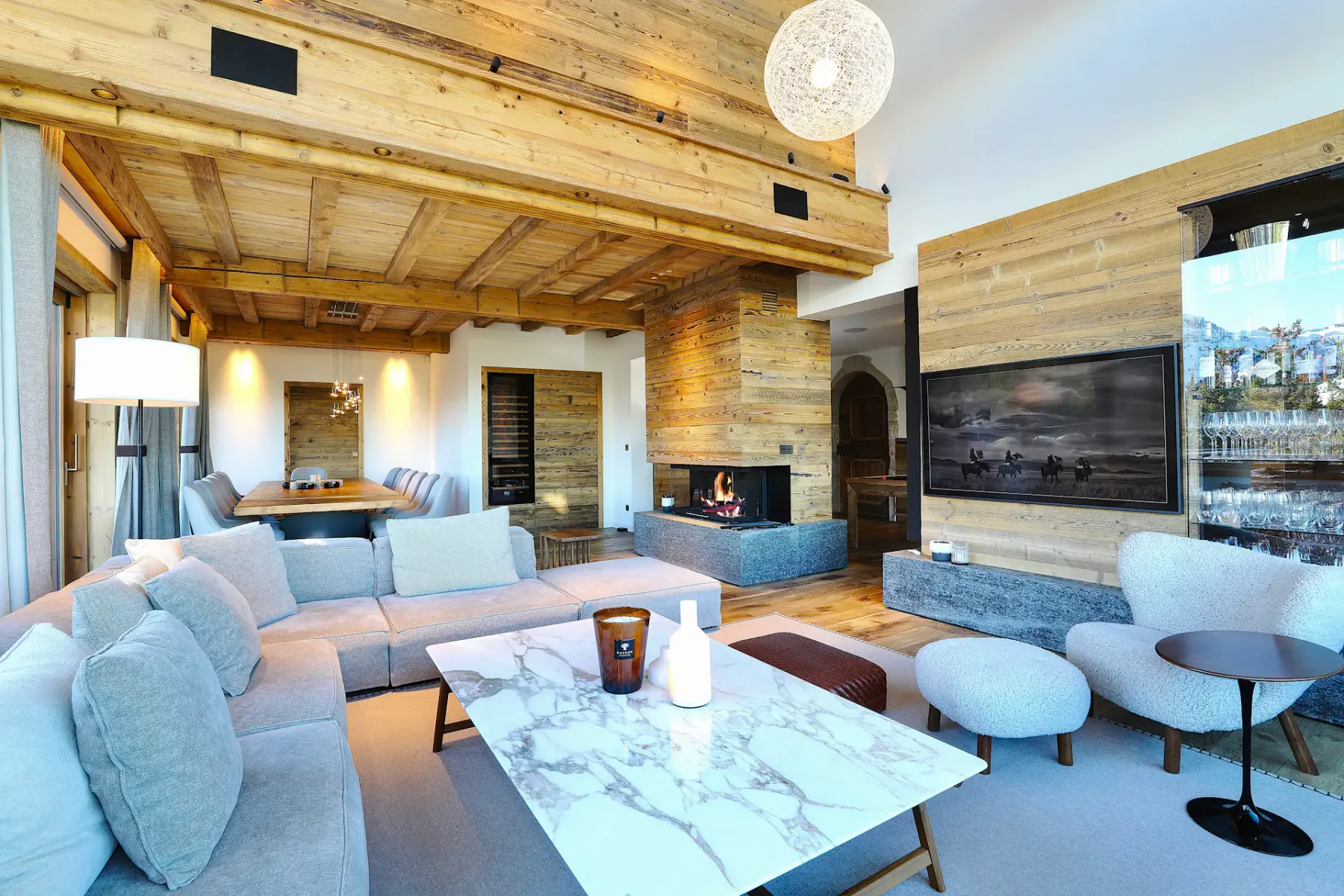 A living room with pale seating, a marble coffee table, and a fireplace.