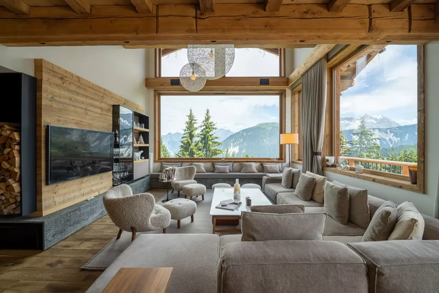 Amplia sala de estar con grandes ventanas, vistas a la montaña, sofá modular beige, decoración moderna y detalles de madera.