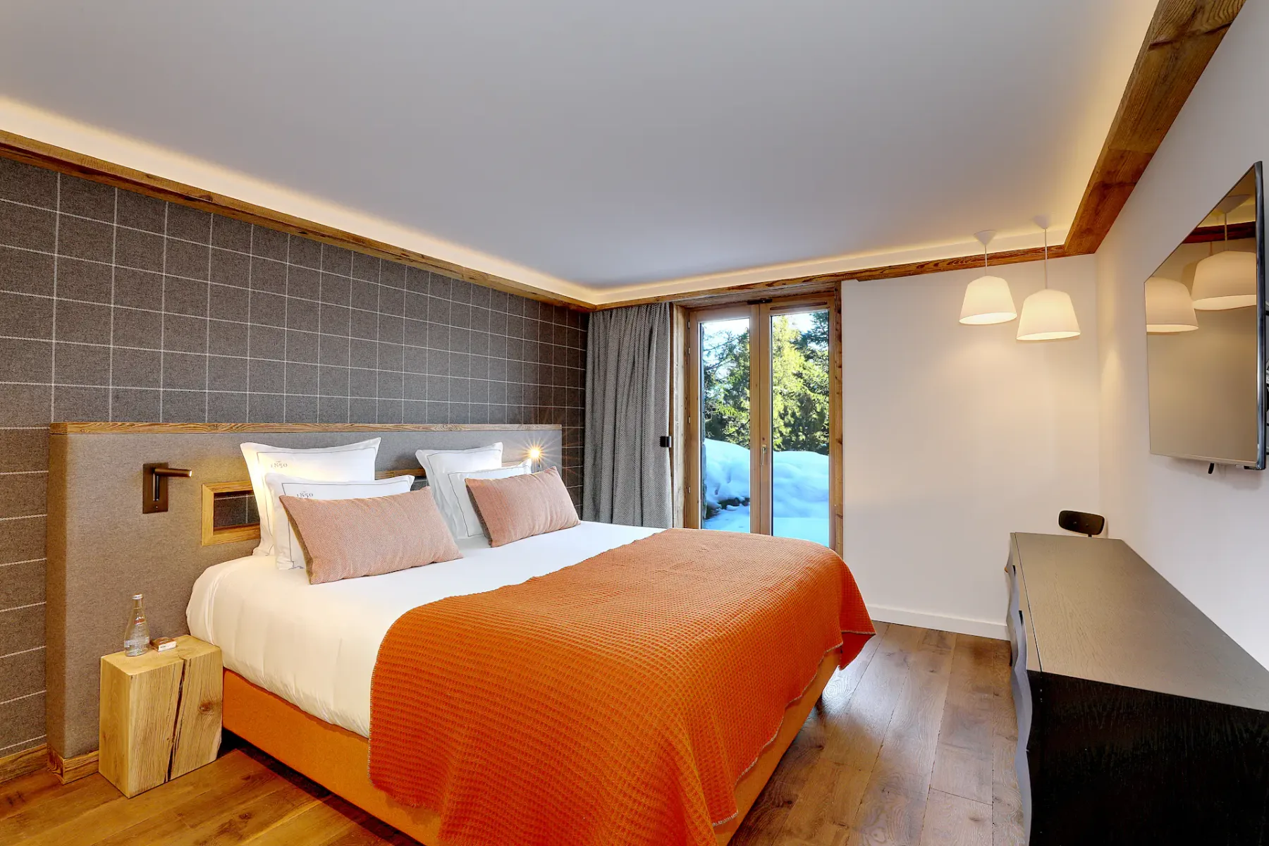 Un dormitorio con una cama grande vestida con ropa de cama naranja junto a una puerta de vidrio.