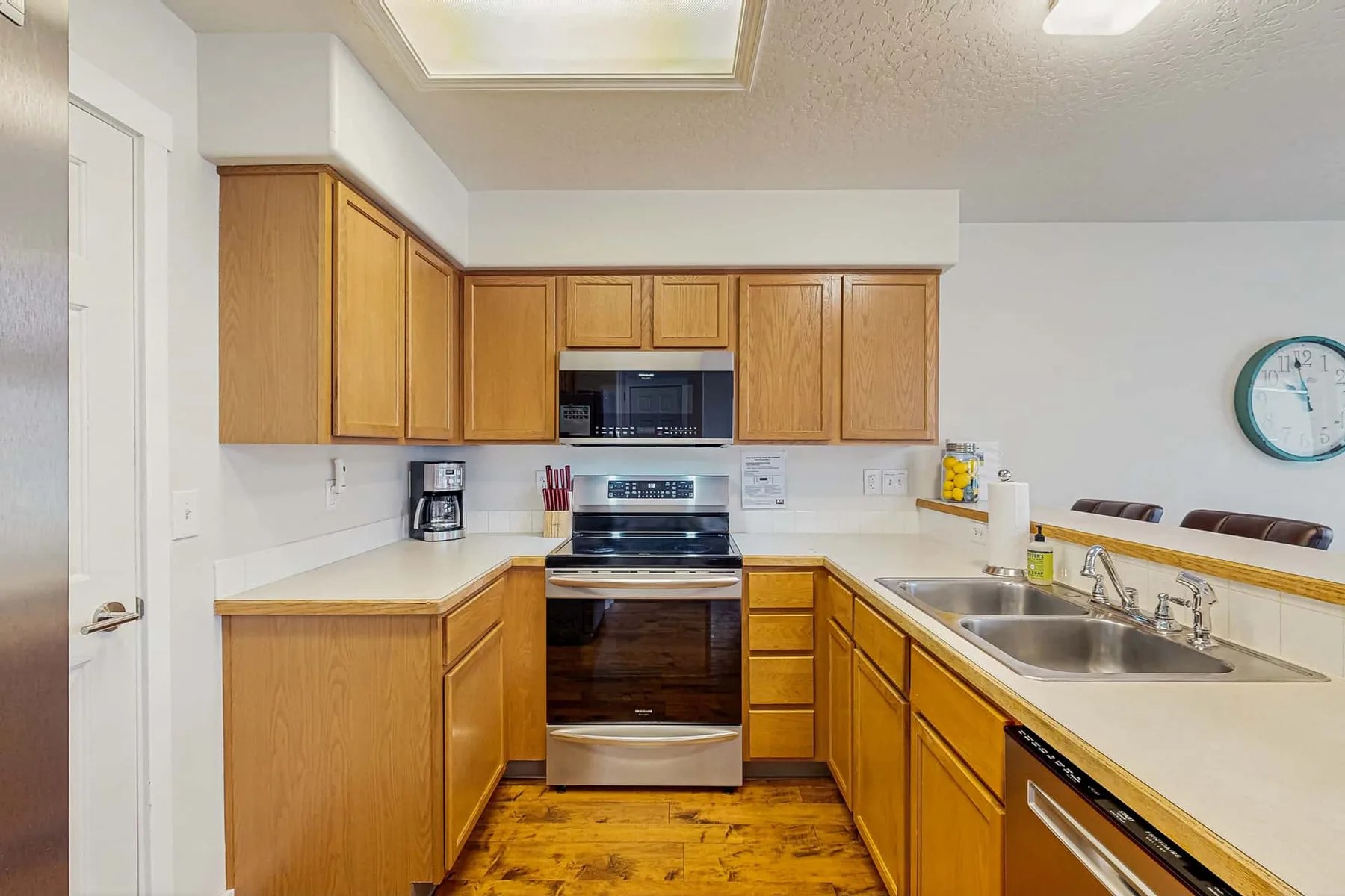 A kitchen with wooden cabinets, an oven, and a sink along the counter.