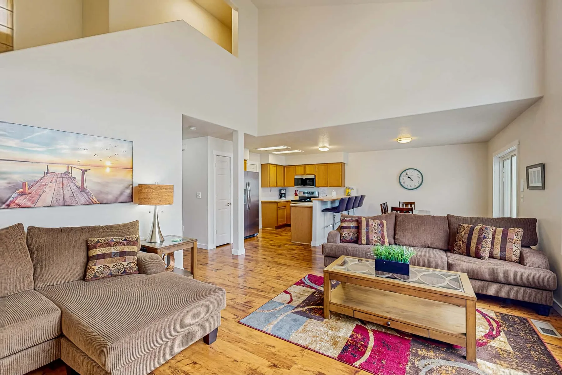A spacious living room with seating around a coffee table and a colorful rug.