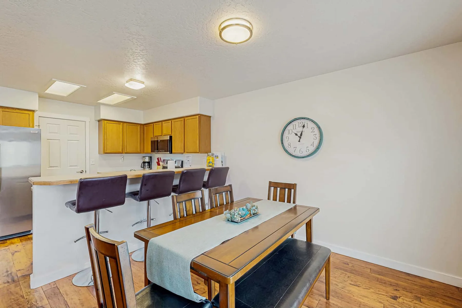 A dining area with a wooden table and kitchen cabinets in the background.