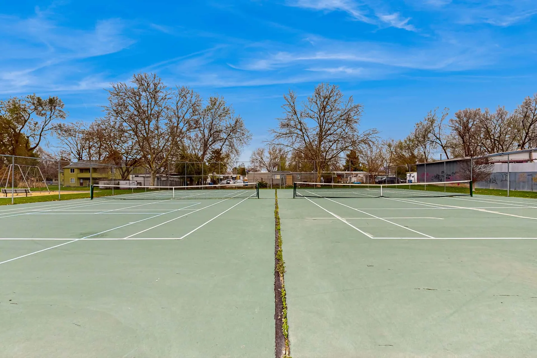 Outdoor tennis courts sit beneath a clear blue sky.
