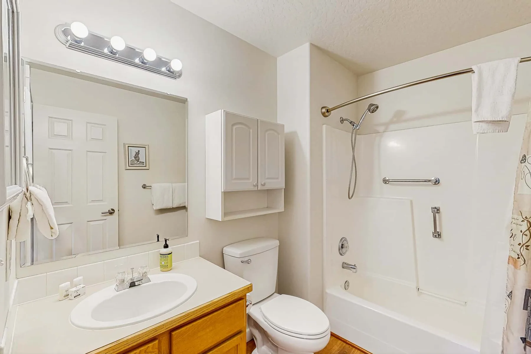 A bathroom with a sink, mirror, toilet, and bathtub with shower.