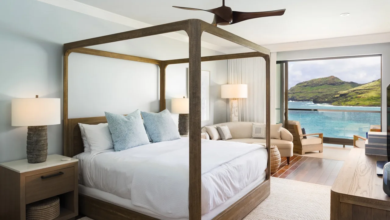 Un dormitorio con cama con dosel y asientos junto a una gran ventana con vistas al agua.
