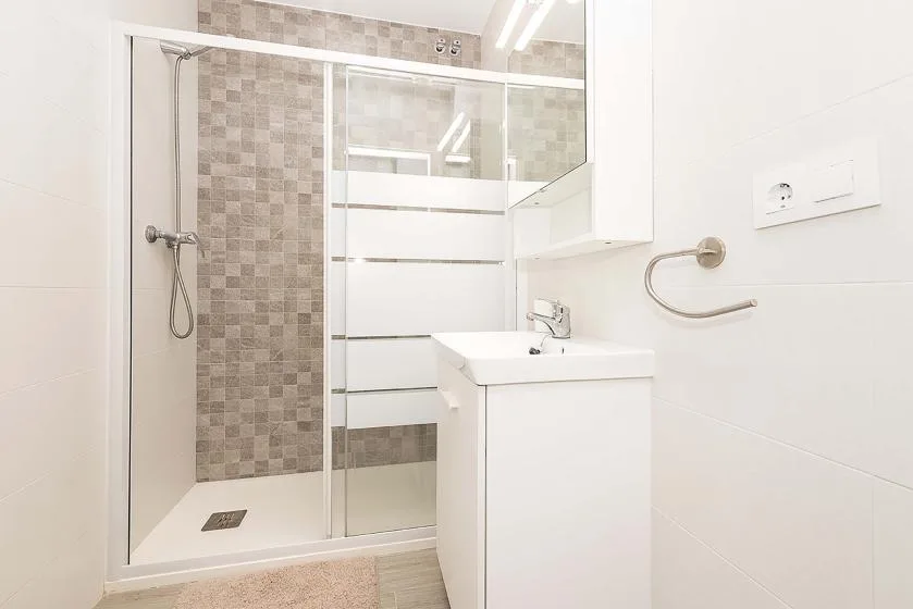 A bright bathroom with a glass shower and a white sink cabinet.