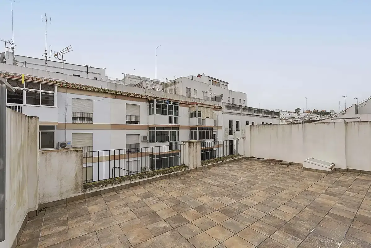 A rooftop terrace with tiled paving and surrounding apartment buildings.