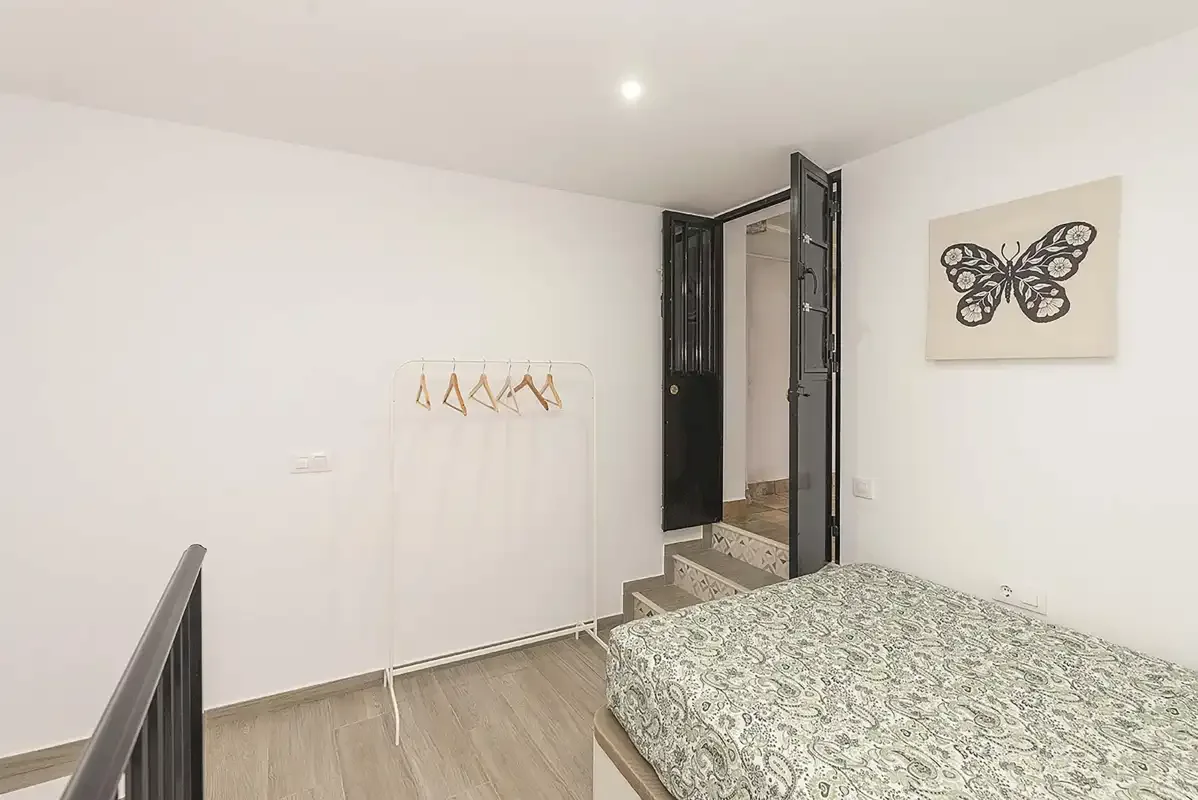 A bedroom with a patterned bedspread and an open doorway.