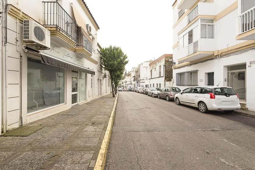 A quiet-looking residential street lined with buildings and parked cars.