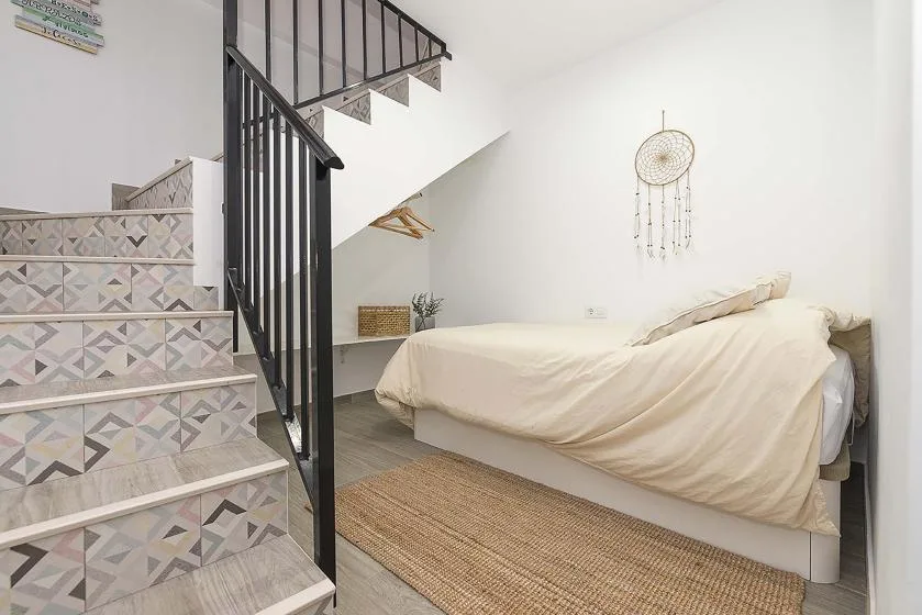 A bedroom with a bed beside a patterned staircase.