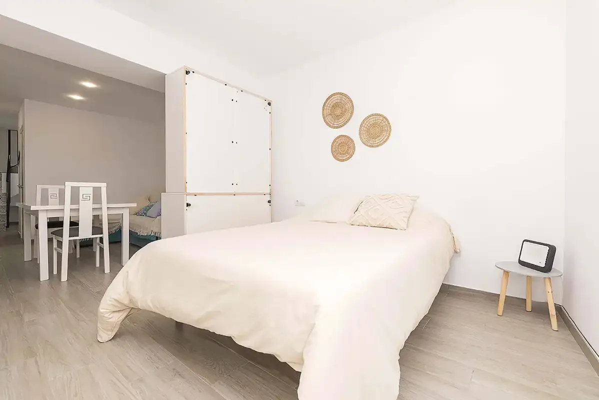A bedroom with a bed and a dining table in the adjoining area.