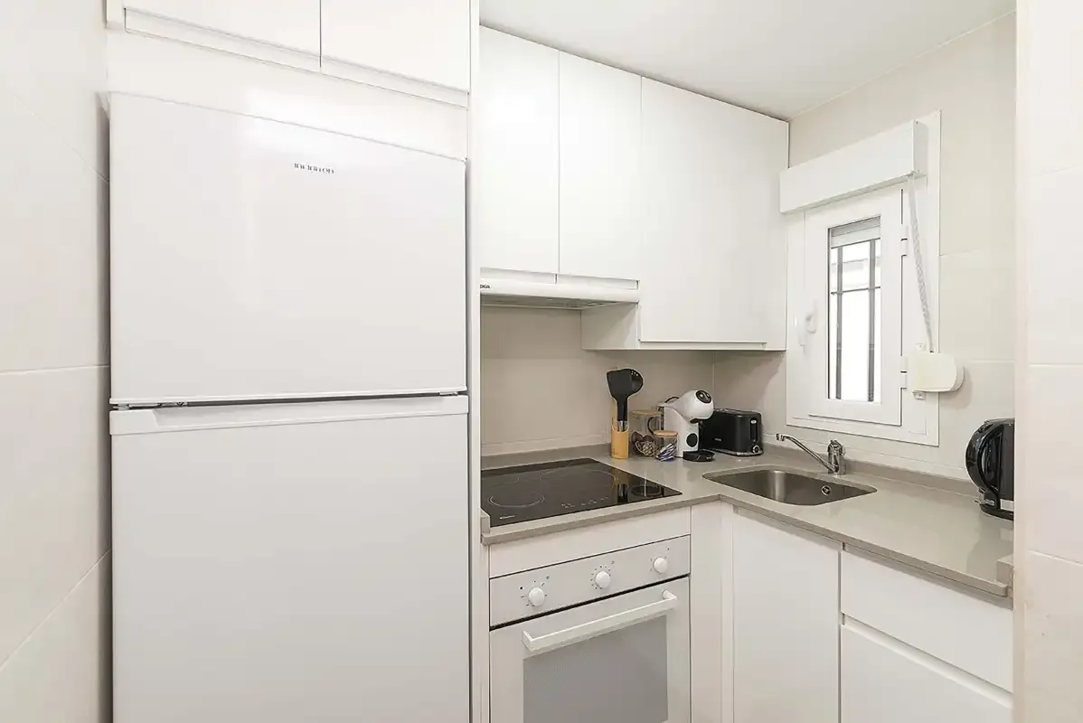A bright kitchen with a refrigerator, cooktop, and sink.
