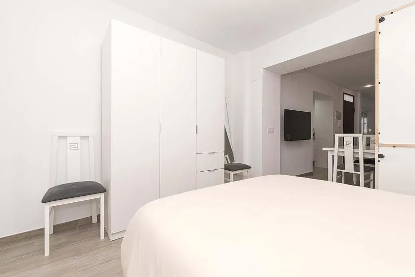 A bright bedroom with a large bed and a white wardrobe.