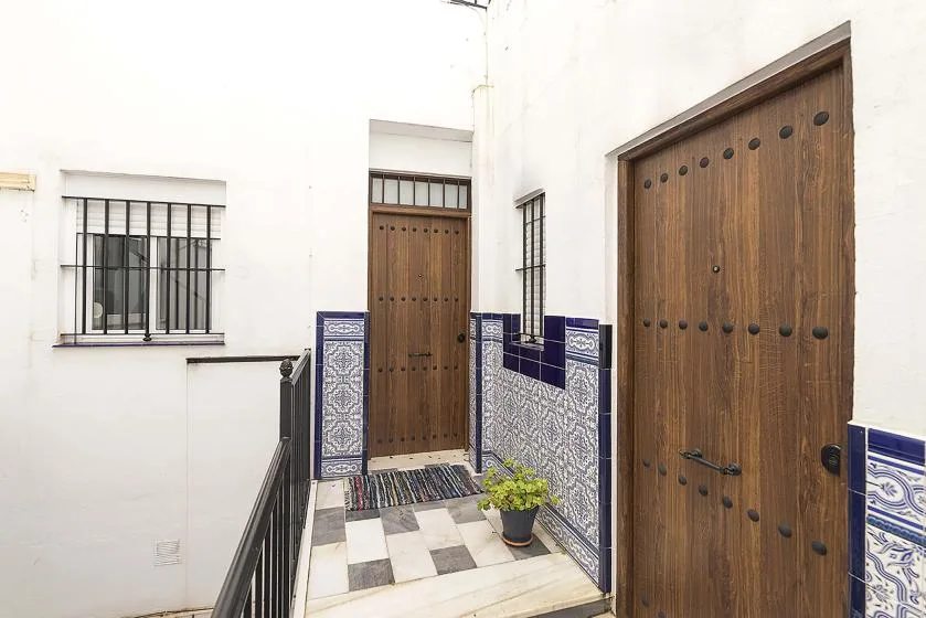 A tiled entry corridor with wooden doors and a potted plant.