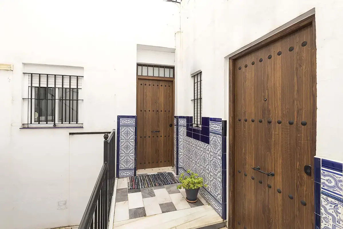 A tiled entrance corridor with wooden doors and a potted plant.