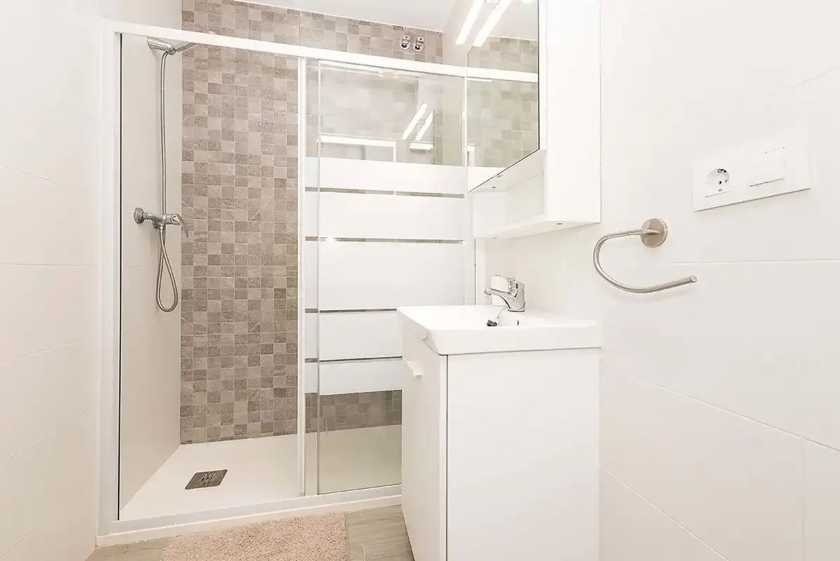 A bright bathroom with a glass shower and white sink vanity.