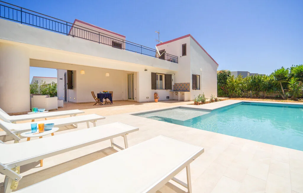 A modern house opens onto a swimming pool and outdoor seating area.