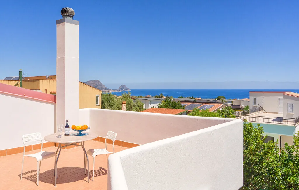 A rooftop terrace with a table and seating overlooks the sea.