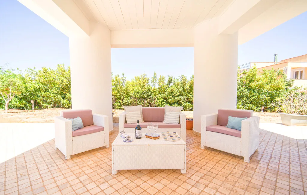 A covered patio seating area with cushioned chairs around a low table.