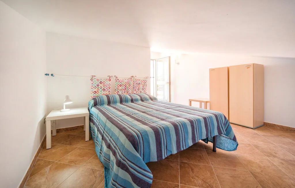 A bright bedroom with a bed covered in striped bedding.