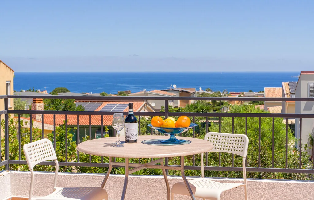 A balcony dining area overlooks nearby rooftops and the sea.