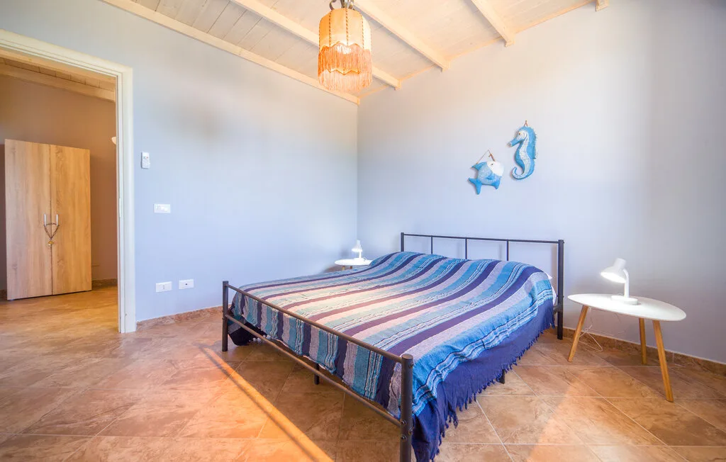 A bedroom with a bed, colorful striped bedding, and a small round table.