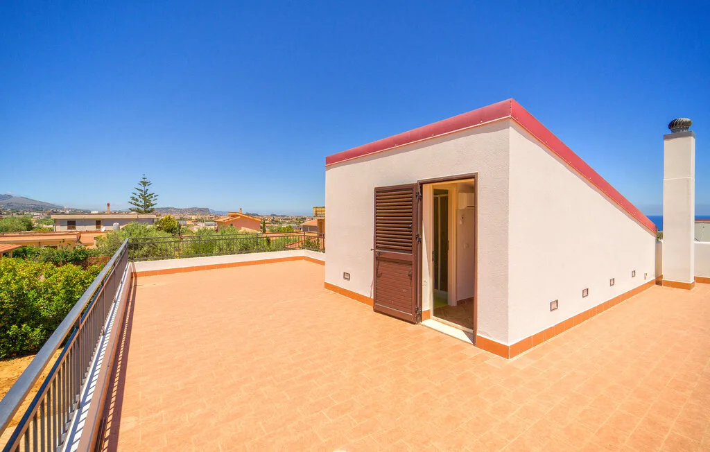 A sunny rooftop terrace with tiled flooring and an open doorway.