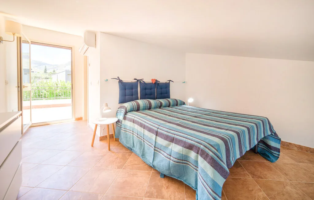 A bedroom with a double bed covered in a striped blue bedspread.