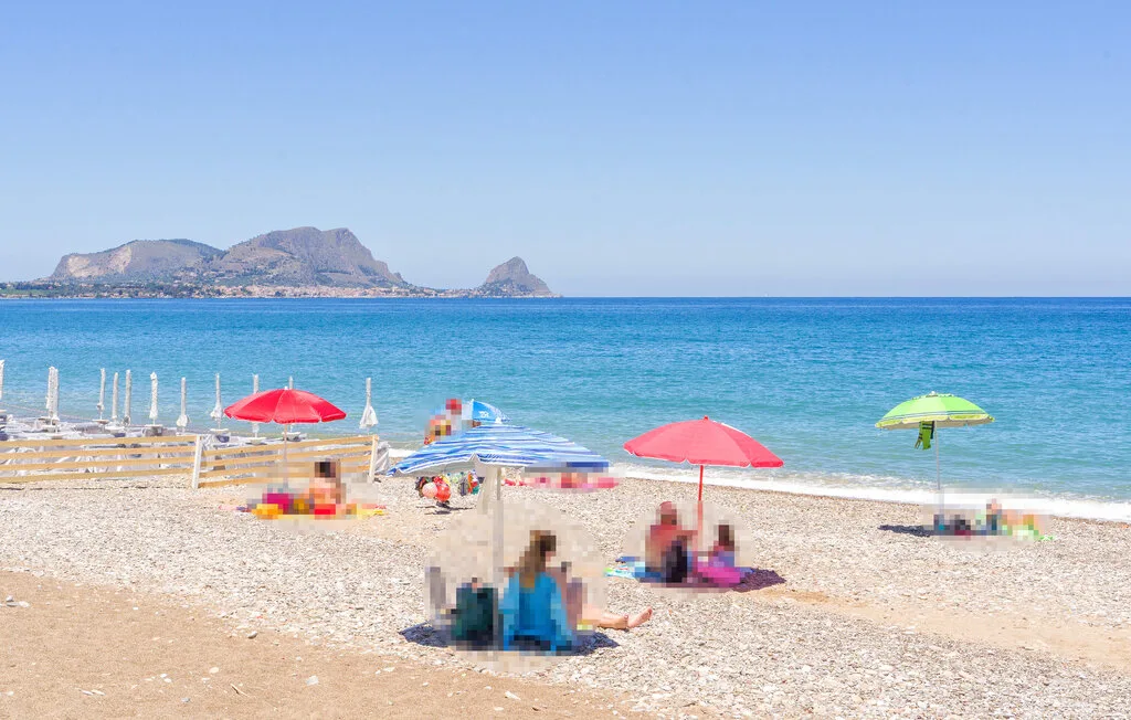 A sunny beach with colorful umbrellas along the shoreline.