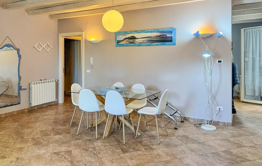A dining area with a table and chairs beneath a hanging light.