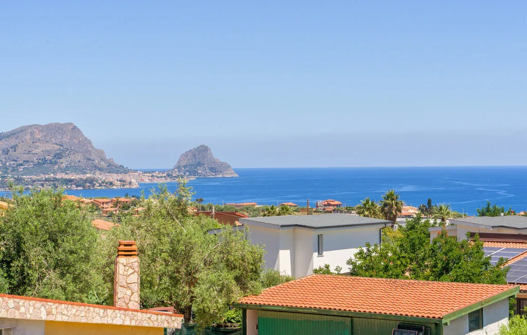 Coastal landscape with blue sea, distant rocky headlands, and rooftops.