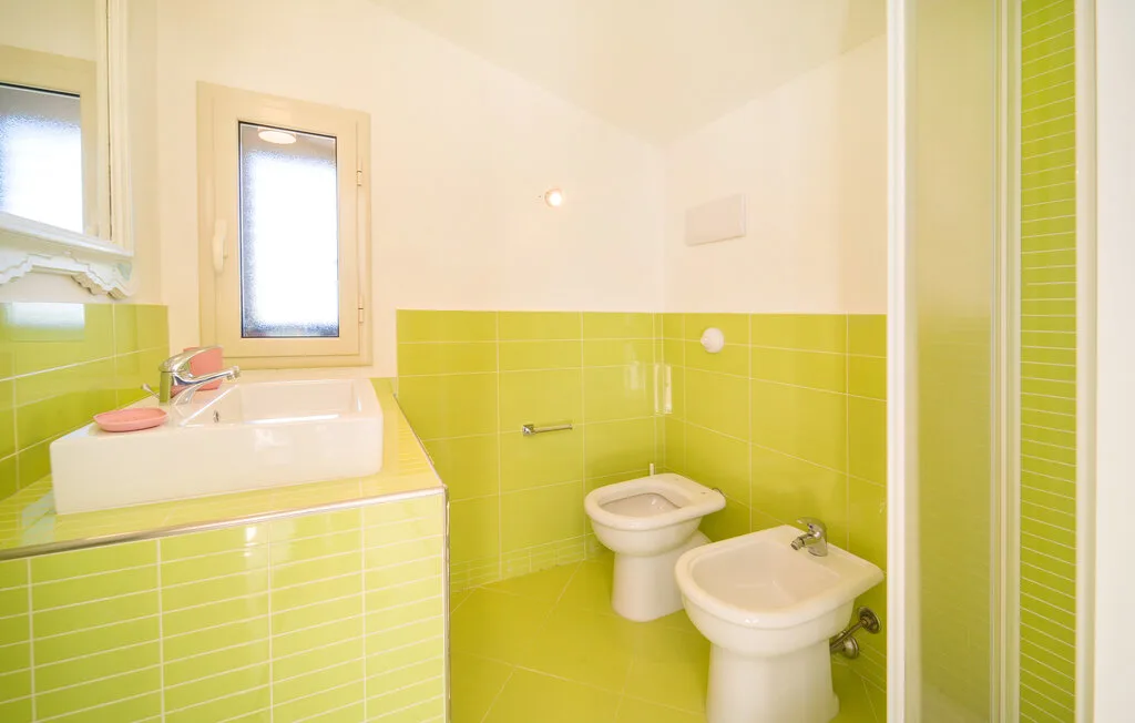 A bright bathroom with a sink, toilet, bidet, and shower.