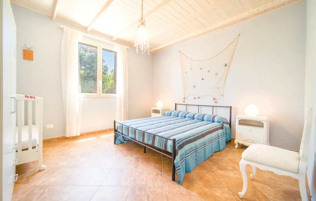 A bedroom with a double bed, a window, and light-colored walls.