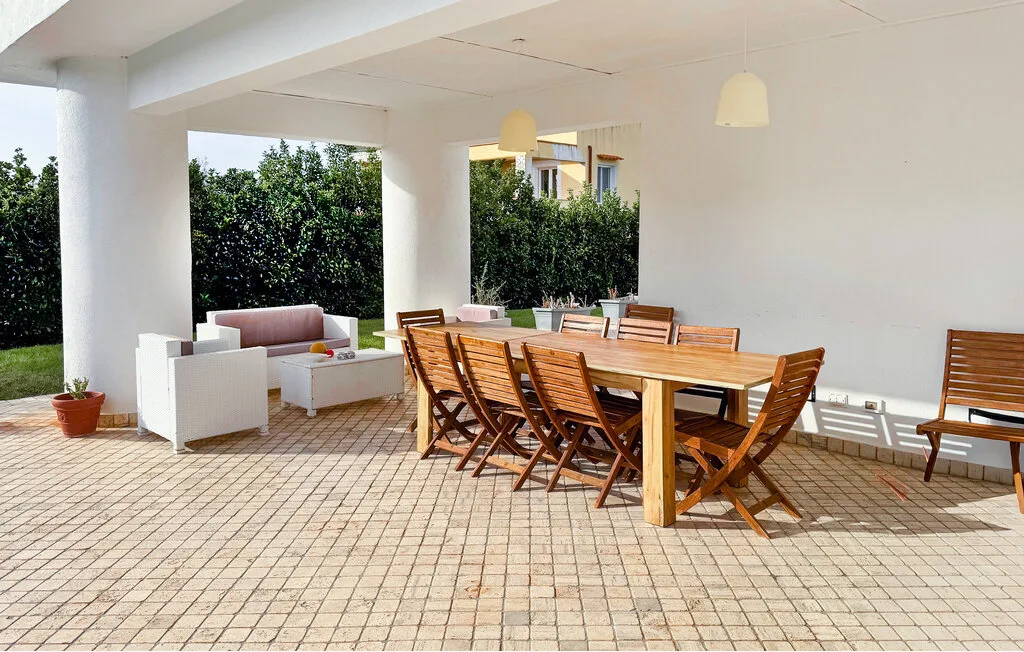 A covered patio with a wooden dining table and outdoor seating.