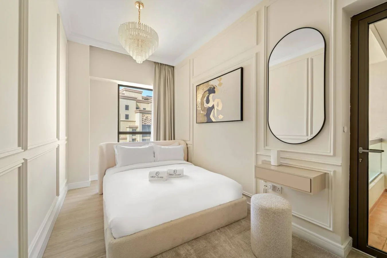 Un dormitorio luminoso con una cama bien tendida y un espejo grande.