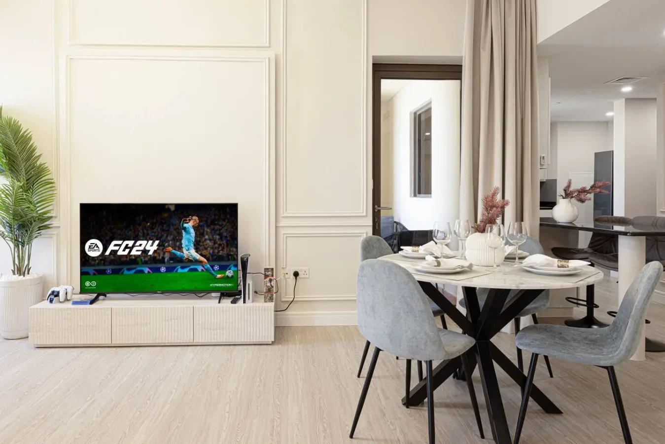 Un comedor luminoso con la mesa puesta junto a un televisor.
