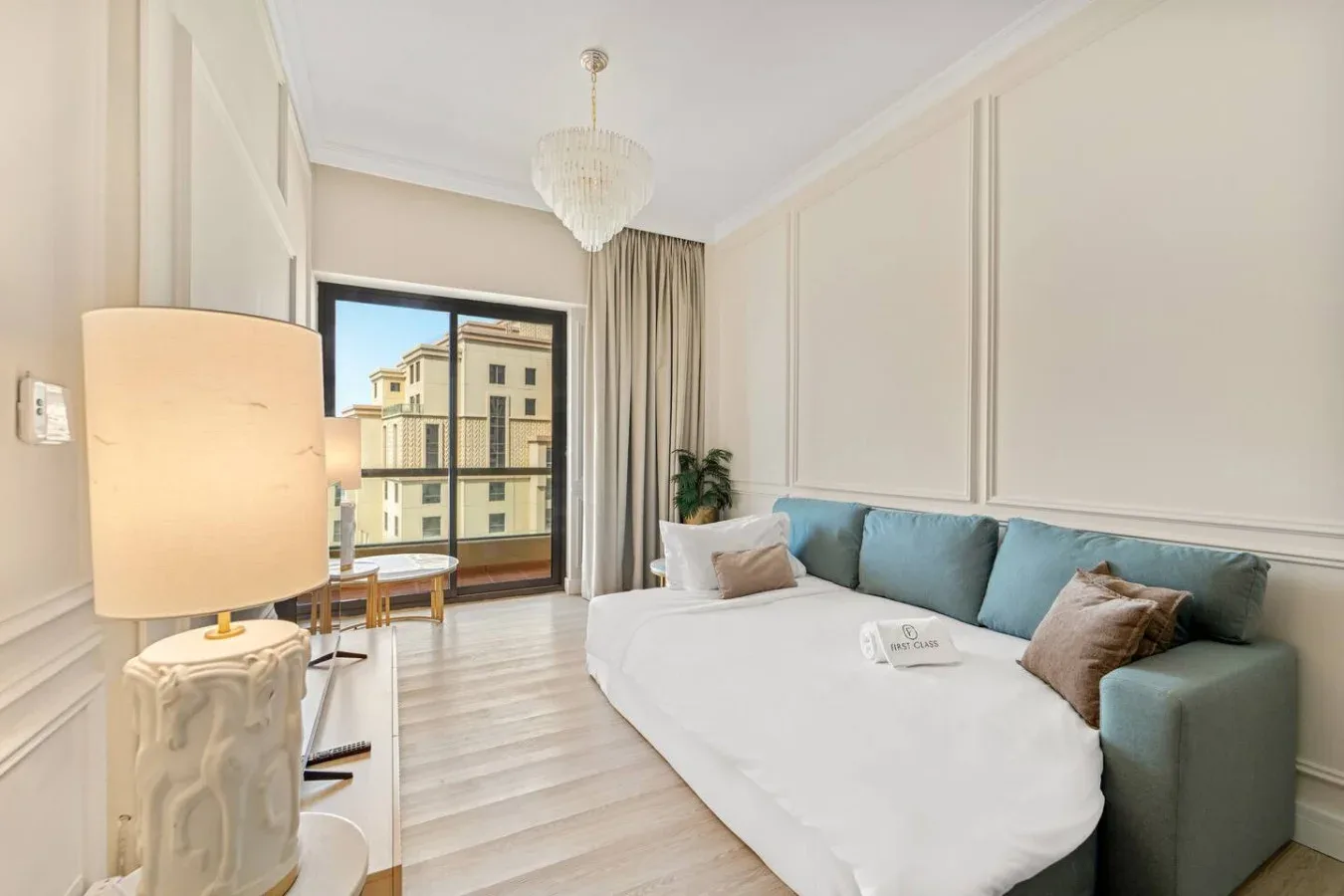 Un dormitorio luminoso con cama, asientos azules y una ventana grande.