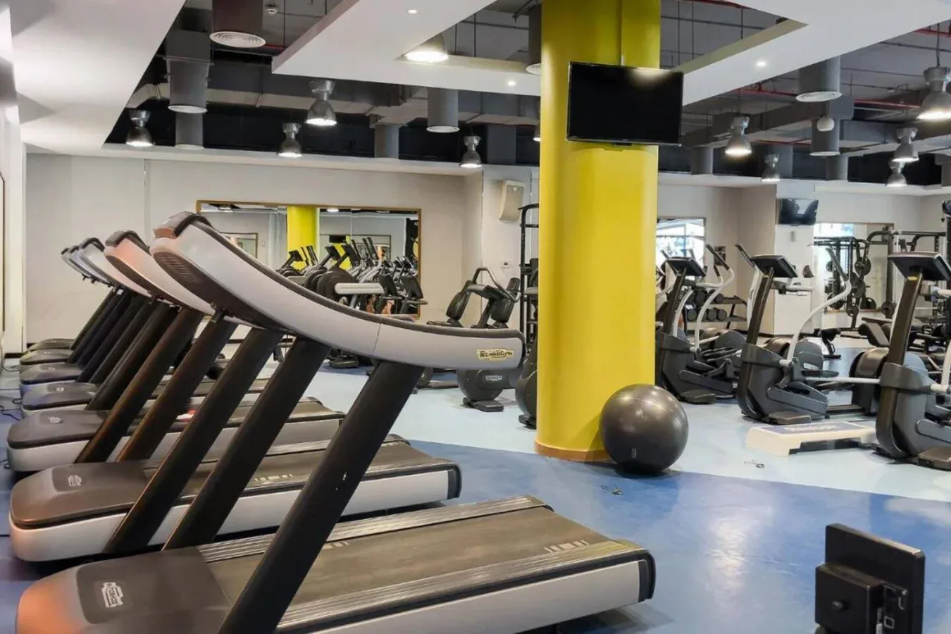 Un gimnasio con cintas de correr y otros equipos de ejercicio.