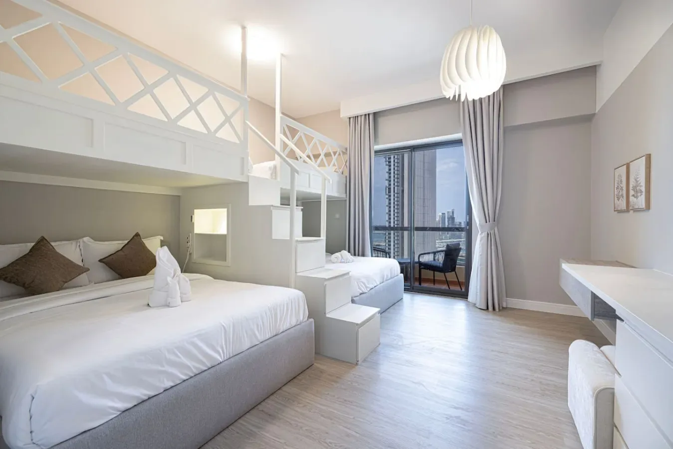 Un dormitorio luminoso con ropa de cama blanca y una gran ventana con edificios cercanos a la vista.