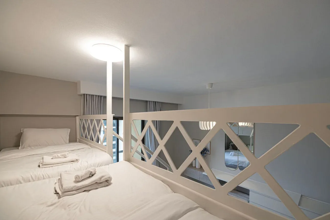Una zona para dormir con ropa de cama blanca está junto a una barandilla decorativa.
