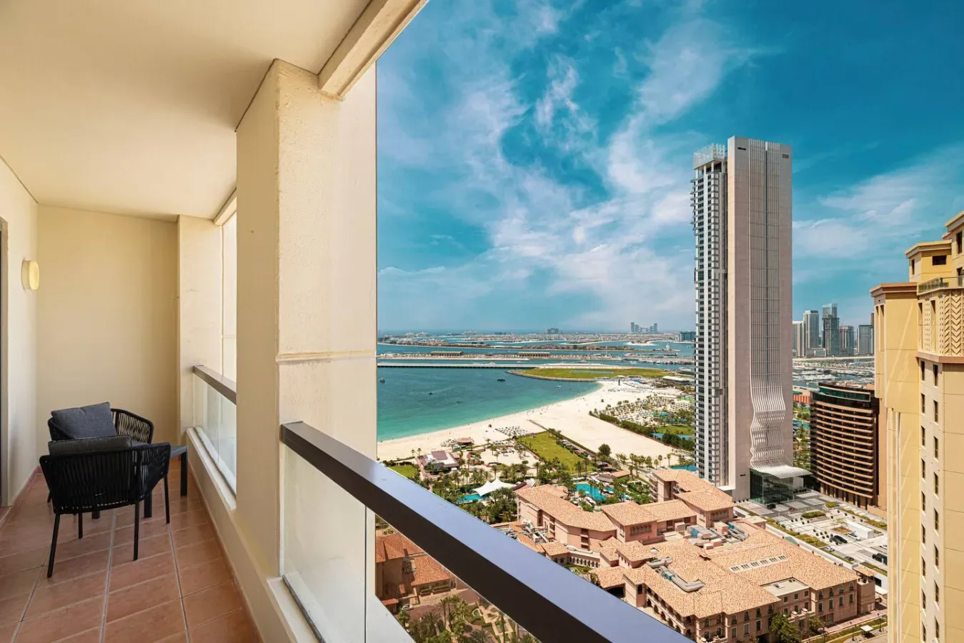 Un balcón ofrece vistas a la playa, el agua turquesa y el horizonte urbano.