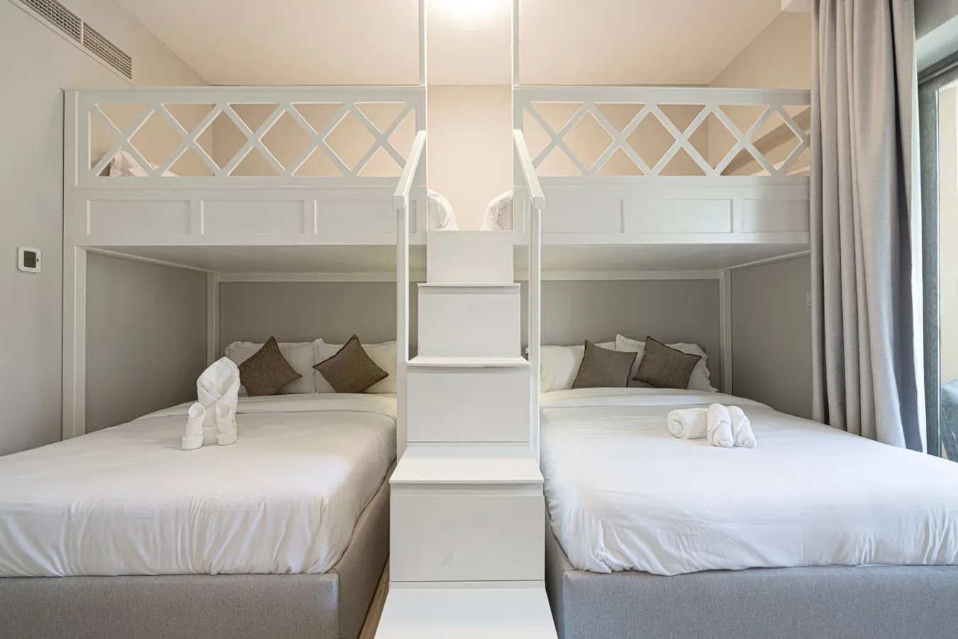 Un dormitorio con dos camas, cojines decorativos y un separador central integrado.