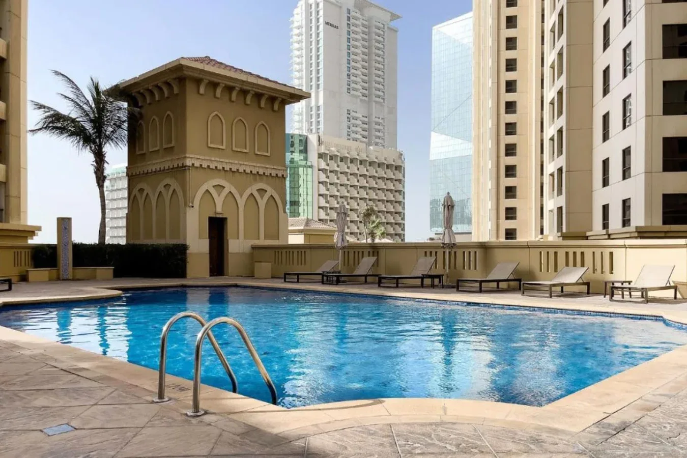 Una piscina en la azotea está rodeada de asientos y edificios altos.