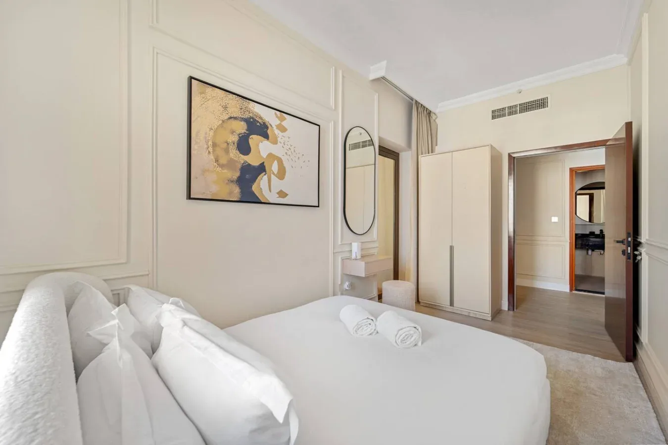 Un dormitorio con una cama bien hecha y una obra enmarcada en la pared.