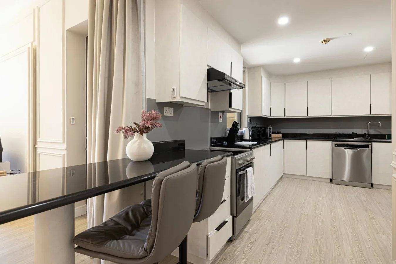 Una cocina luminosa con gabinetes blancos y una encimera oscura.