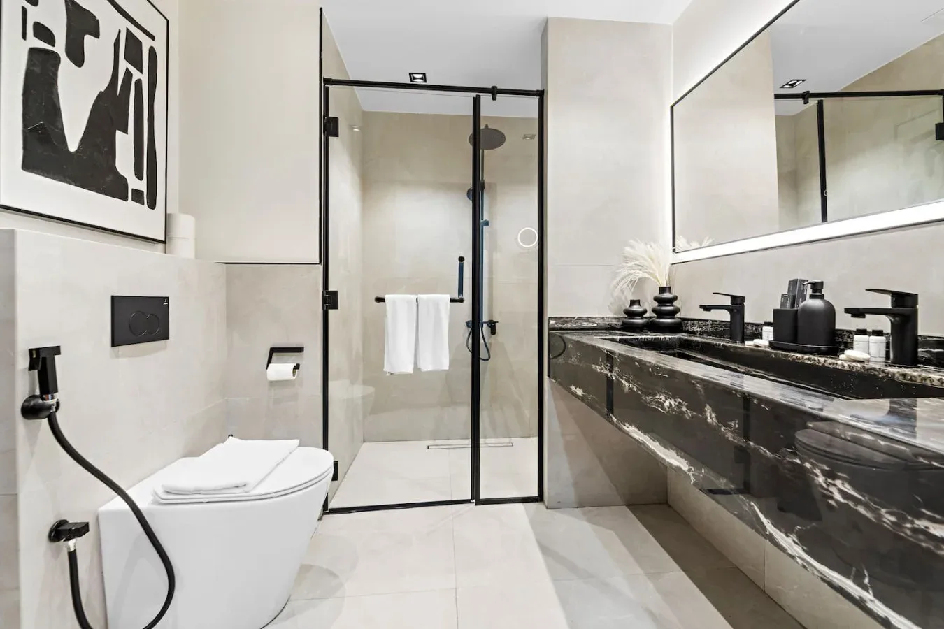 Un baño moderno con una ducha de vidrio y un lavabo alargado.