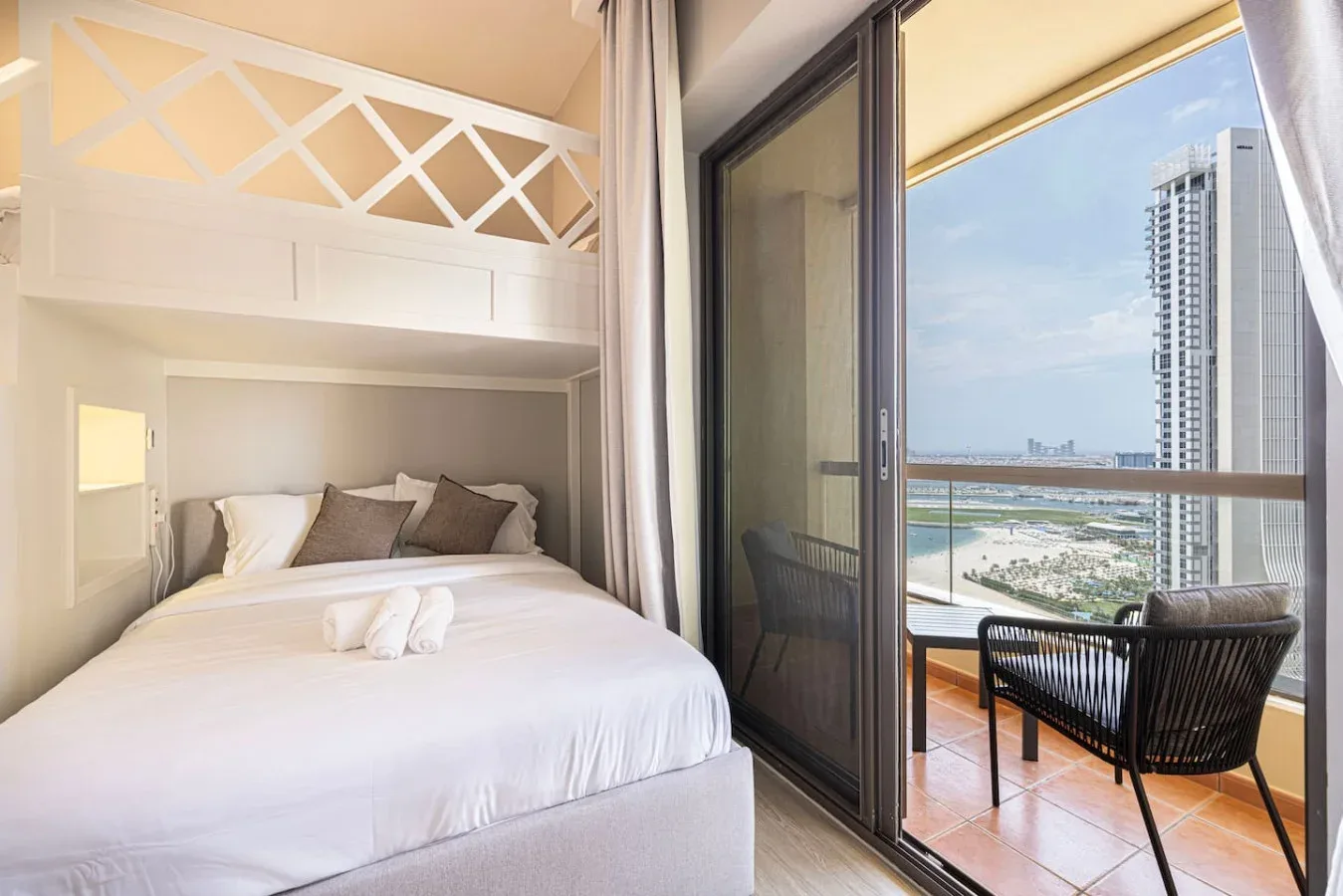 Un dormitorio da a un balcón con asientos y vistas a la costa.