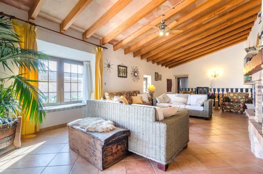 Una sala de estar luminosa con asientos tejidos bajo vigas de madera vistas.