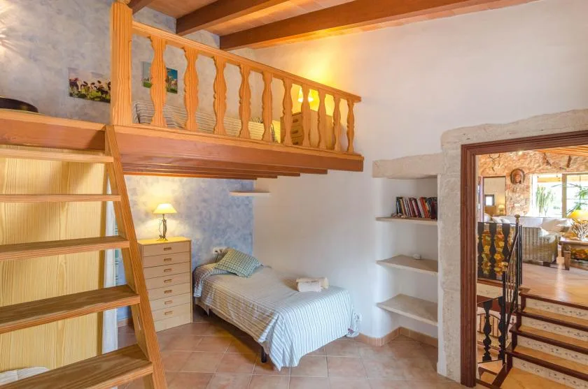 Un dormitorio con una cama alta, una escalera y una cama individual debajo.